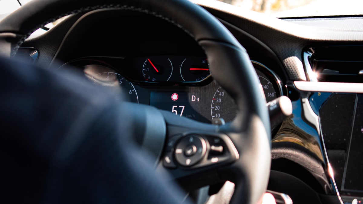 Close-up view of a car dashboard and steering wheel, featuring a digital speedometer display.